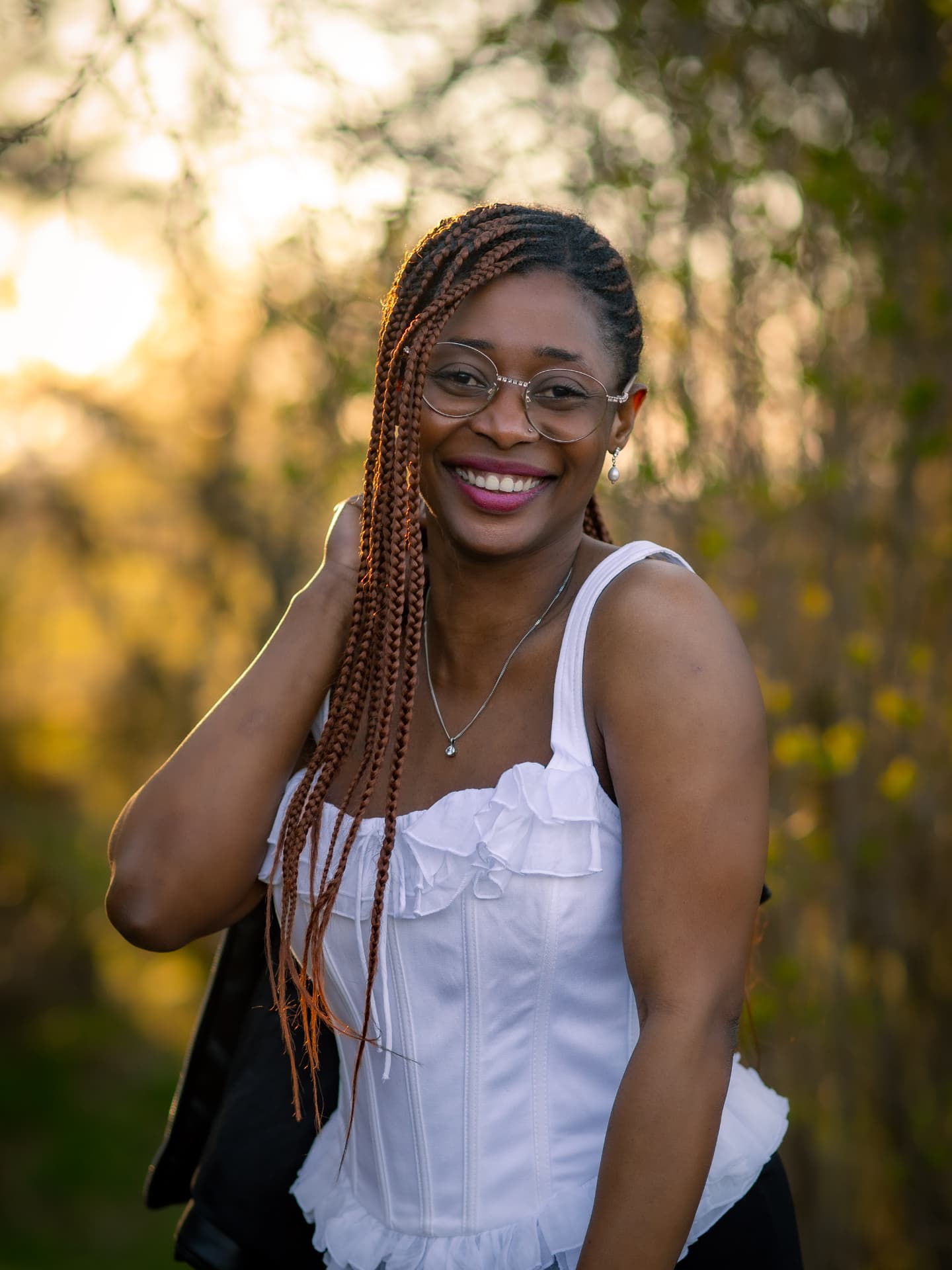 Jamirah smiling in a white top in golden evening light among blossoming trees